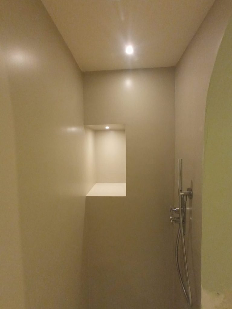 Doccia moderna in resina a Crocetta Torino: rivestimento continuo, nicchia con illuminazione e rubinetteria di design per un bagno elegante e funzionale.